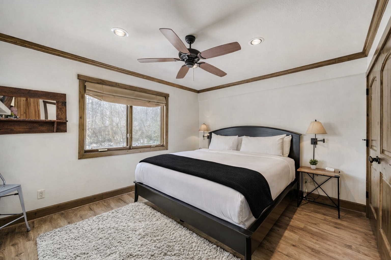 Retire to this quiet, modern bedroom featuring a comfortable bed, ceiling fan, and large windows with natural light and views. It's the perfect escape after a busy day.