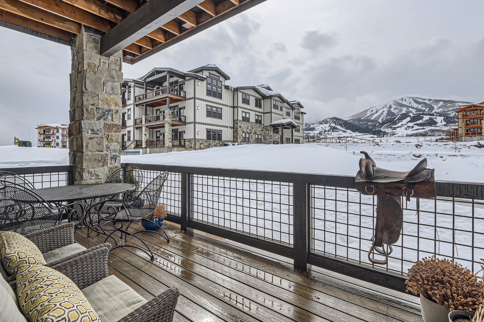 Snowy mountain vistas spread out before you from this covered terrace, where rustic stone columns and cozy seating invite you to sip your morning coffee while ski slopes beckon in the distance.