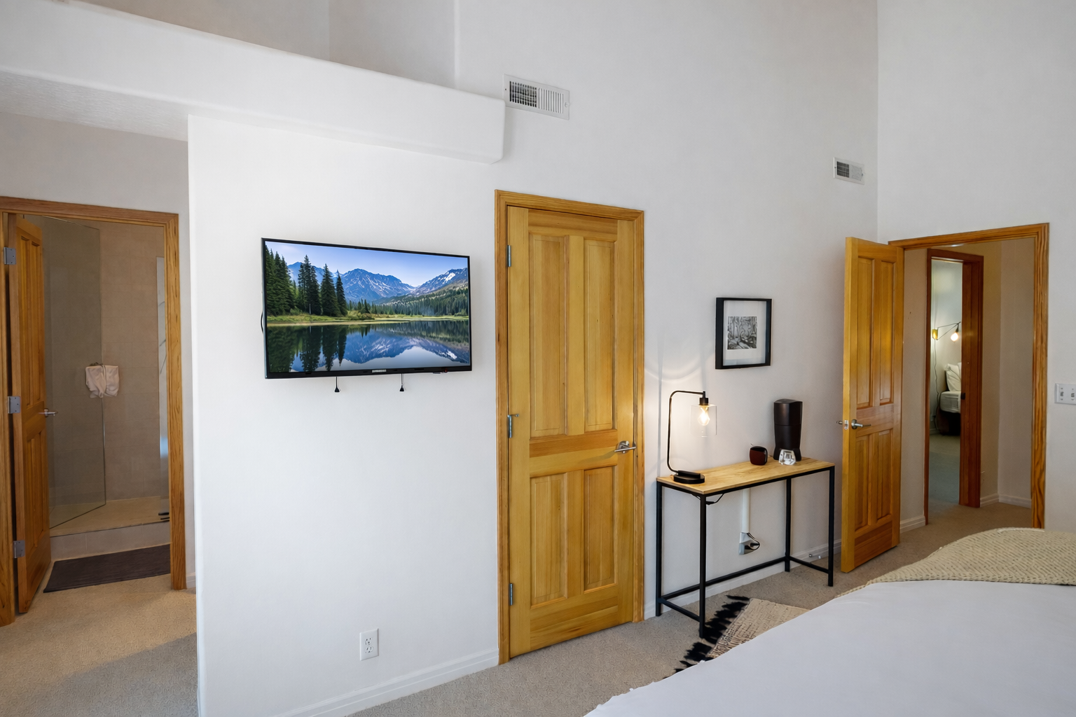 Retreat to this tranquil bedroom featuring a plush king-sized bed, a bright vaulted ceiling, and views of lush greenery for a serene escape.