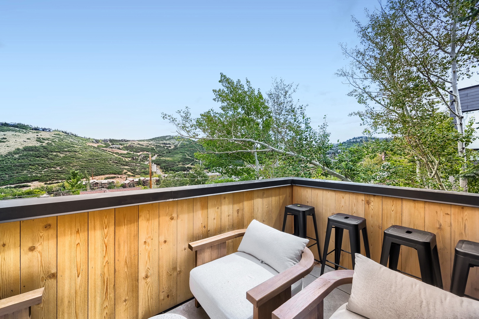 Unwind on your private terrace with sweeping mountain views. Soft seating, bar-style stools, and natural wood surround you for morning coffee or evening relaxation under open skies.
