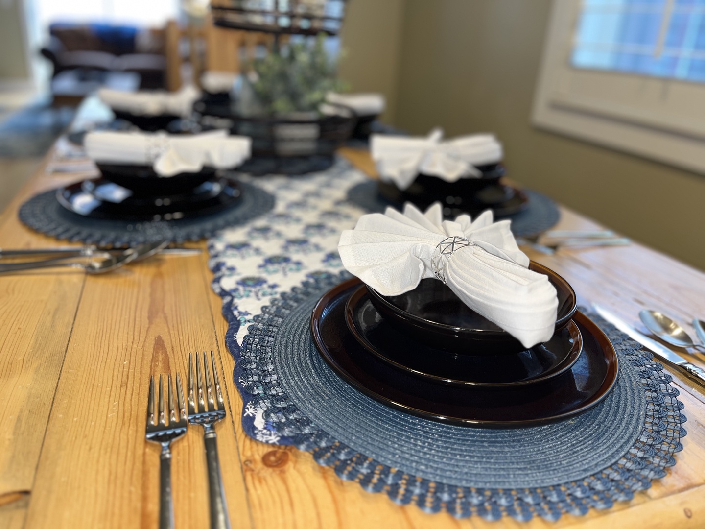Gather around this rustic wooden dining table, featuring a mix of high-back chairs and bench seating. The space is beautifully accented with mountain-inspired decor, a patterned area rug, and soft overhead lighting.