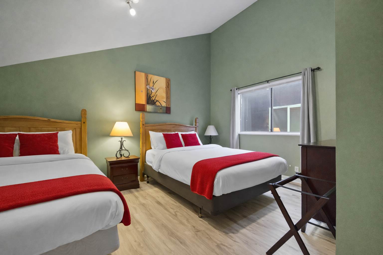 Comfortable & modern double room with stylish red accents, wood flooring, and large windows. A relaxing space for your Park City stay.
