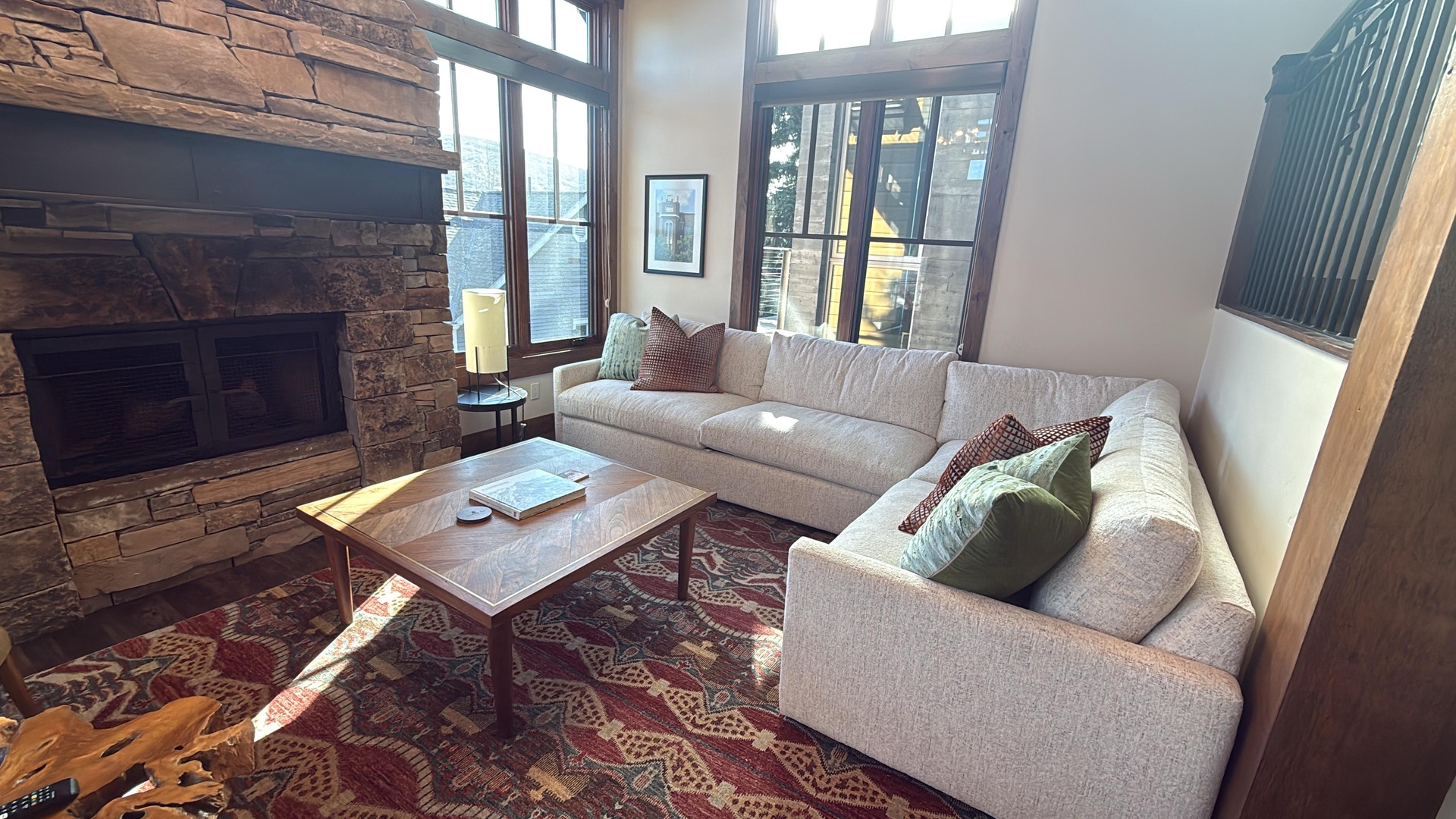 Unwind in your cozy living room with a crackling stone fireplace, plush sectional, and sunlight streaming through tall windows—perfect for relaxing after a day of adventure.
