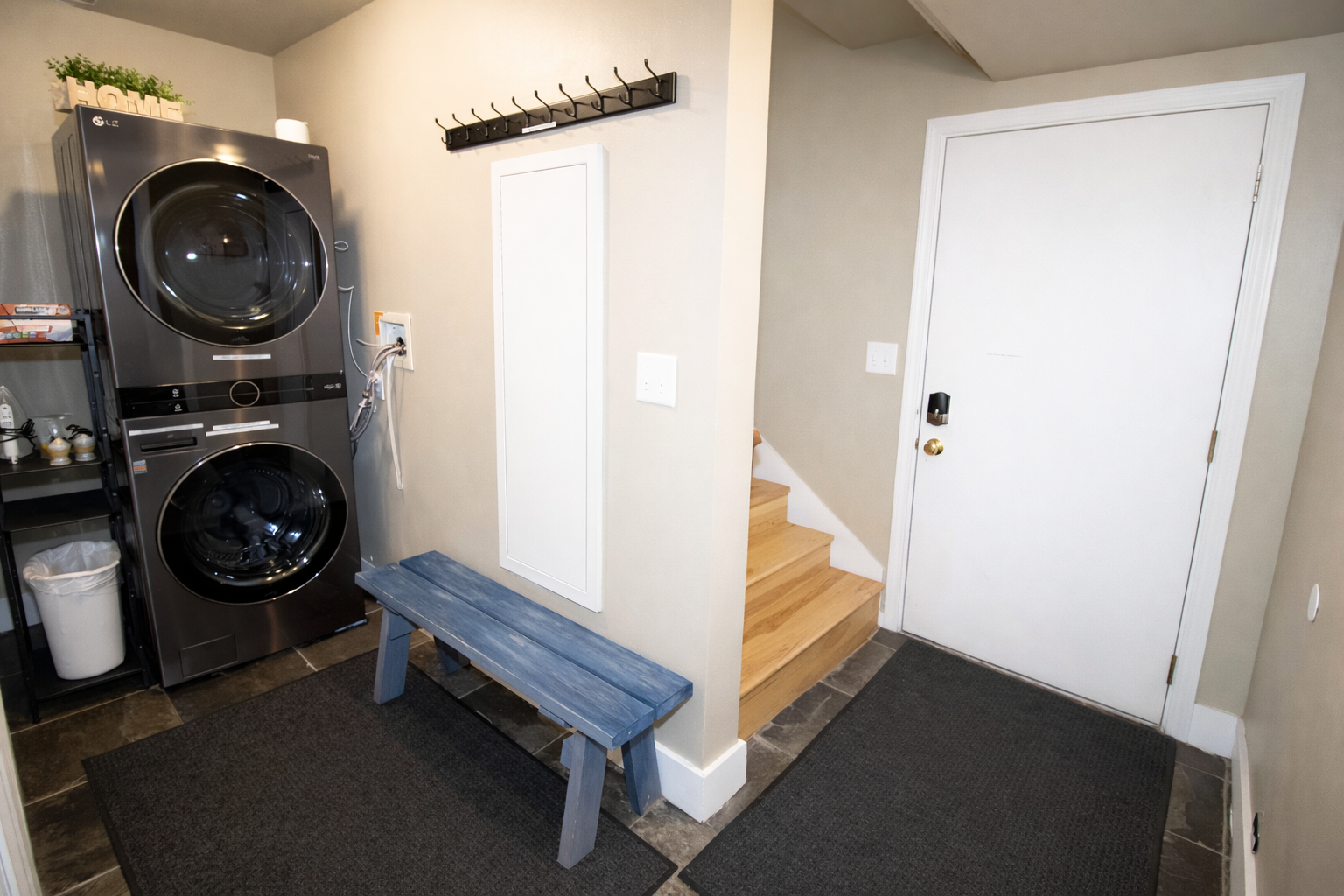 Your dedicated laundry space features modern stacked washer and dryer units, plus convenient storage and a cozy bench for easy clothing prep.