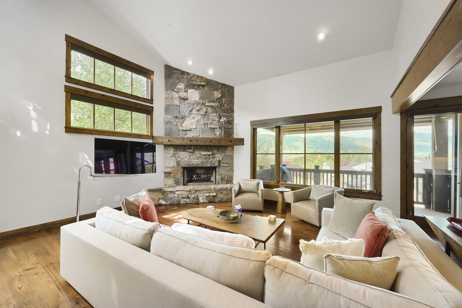 Sink into plush seating by the stone fireplace as natural light fills your airy living space. Floor-to-ceiling windows frame stunning mountain vistas—the perfect backdrop for your mountain getaway.