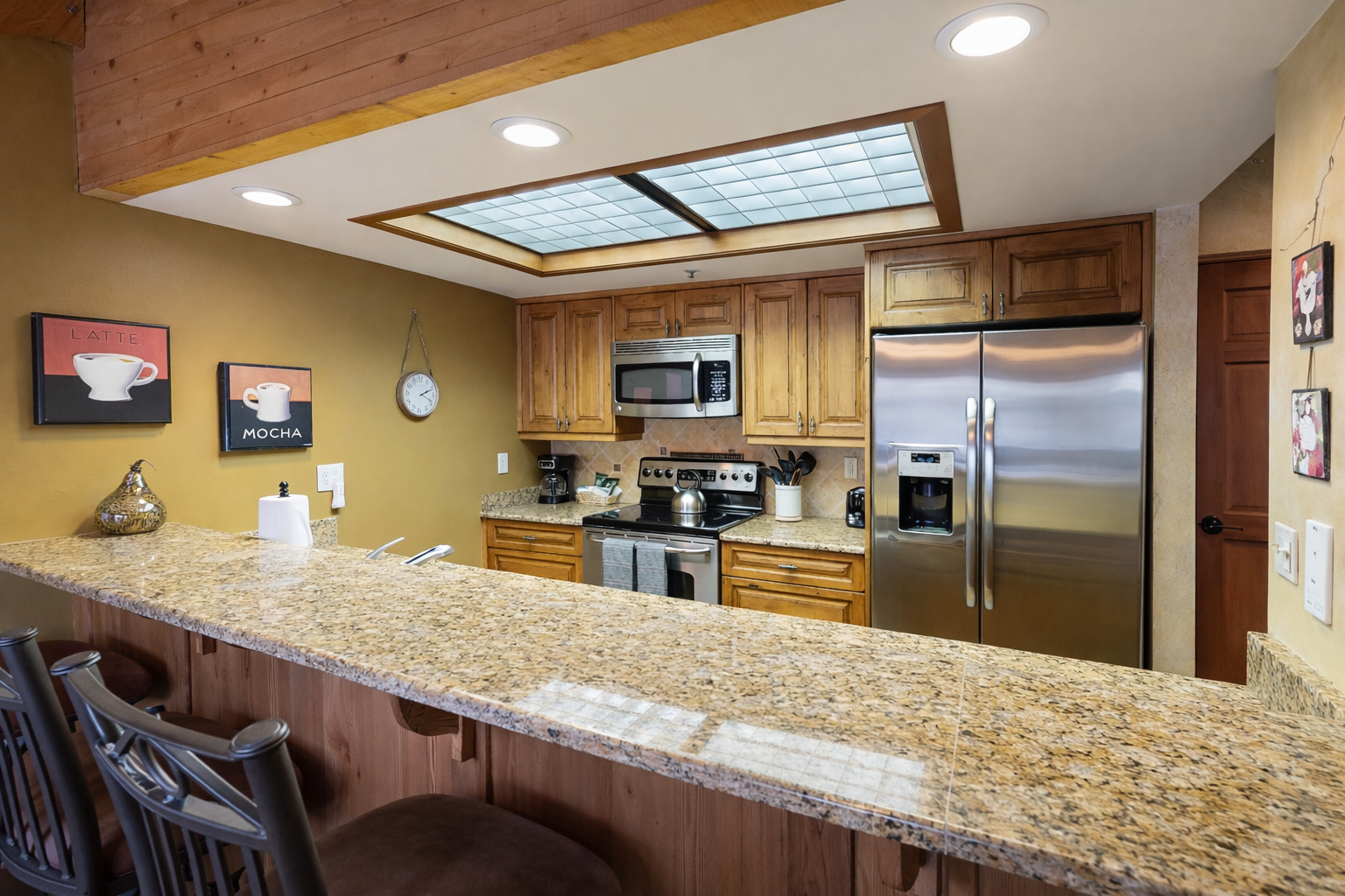 Cook with ease in your fully equipped kitchen featuring granite counters, stainless appliances, and charming exposed beams overhead.