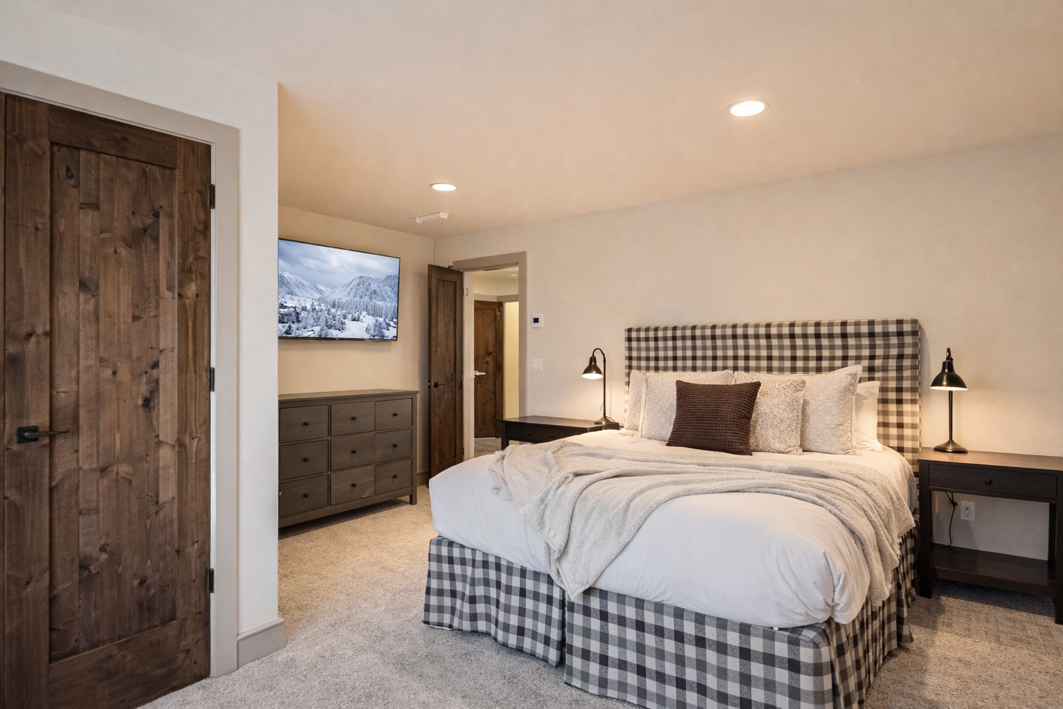 Charming fourth floor bedroom with a plush queen bed, plaid headboard, and TV. A cozy mountain retreat for a restful stay in Park City.