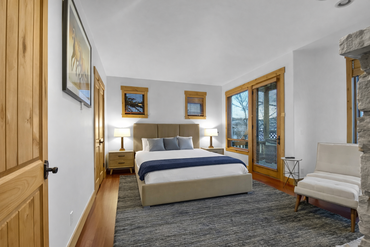 Relax in this bright bedroom featuring a comfortable bed and direct access to a private balcony. Natural light and cozy wood accents create the perfect retreat.