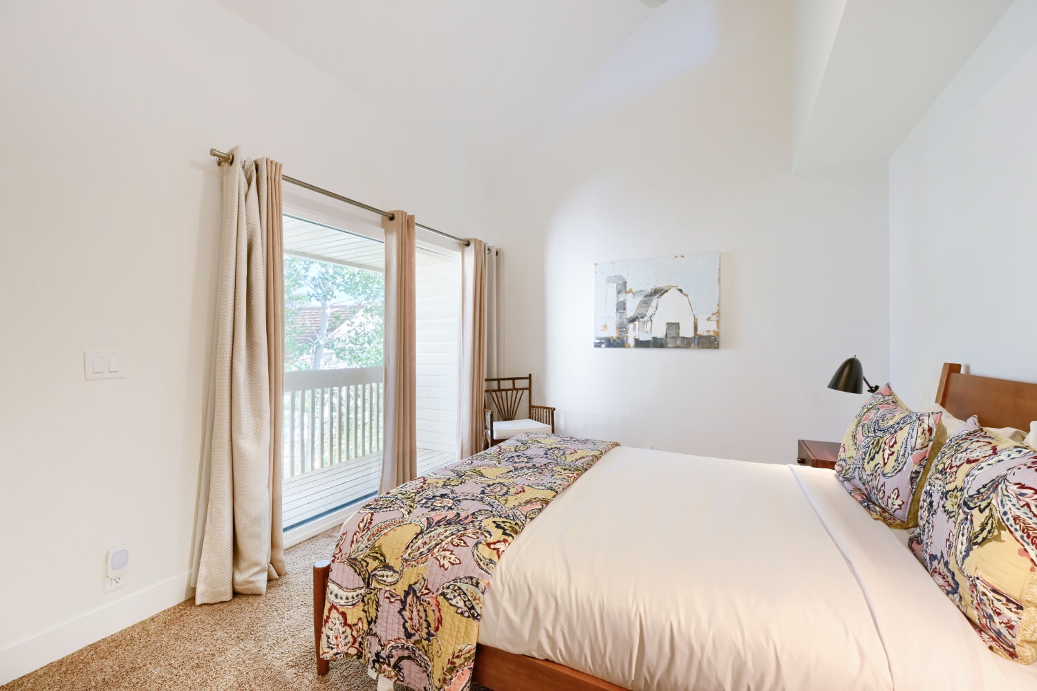 Your serene bedroom retreat features crisp white linens and cheerful patterned accents, with sliding doors opening to a private balcony where fresh air and peaceful views await.