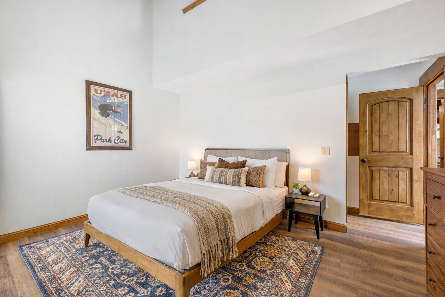 Sink into luxury with your plush queen bed, adorned with soft linens and warm throws. The vintage ski poster adds mountain charm to your peaceful retreat.