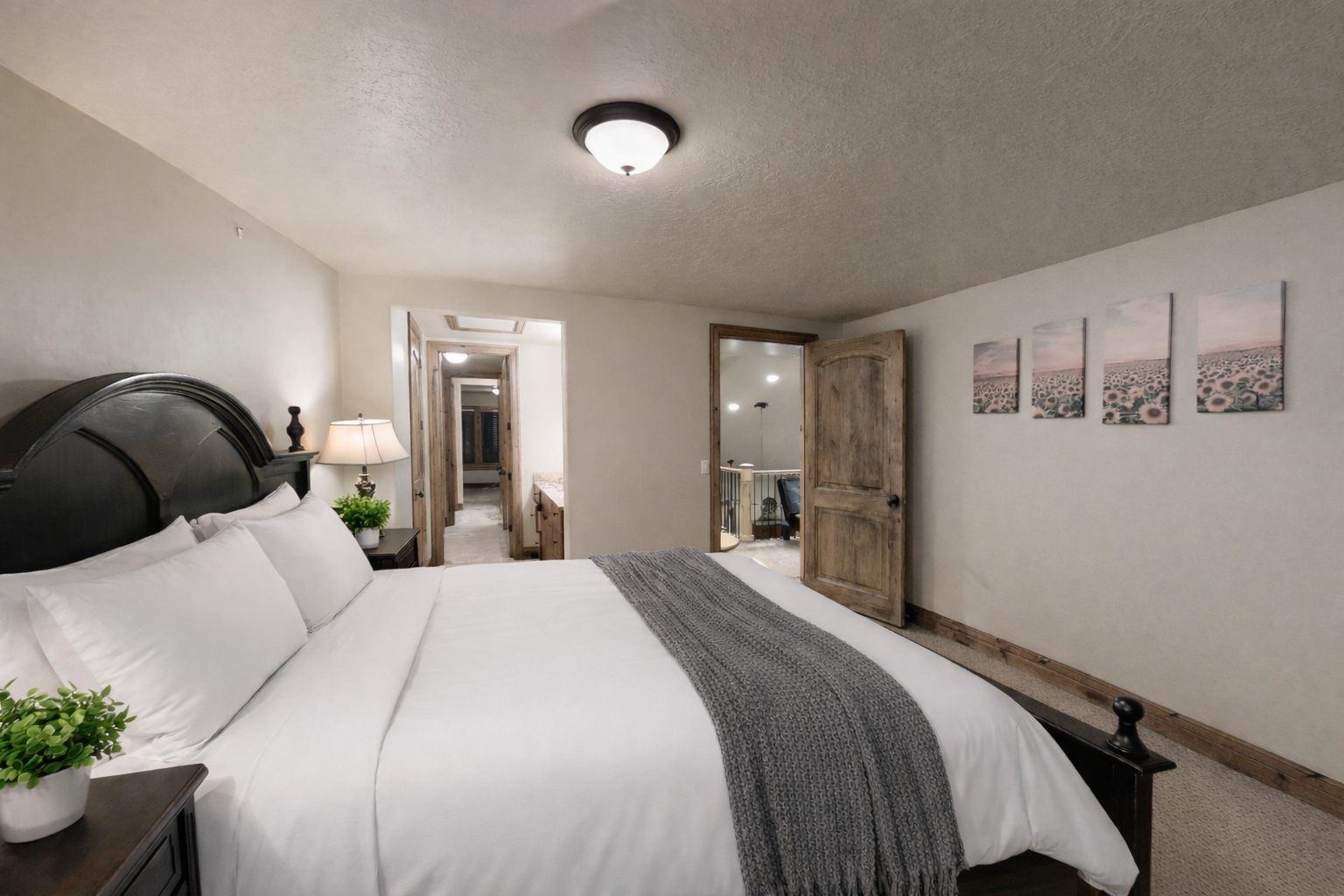 This spacious guest room features a grand four-poster bed, premium linens, and warm bedside lighting. Shuttered windows and plush carpeting create a quiet, comfortable retreat for a restful night.