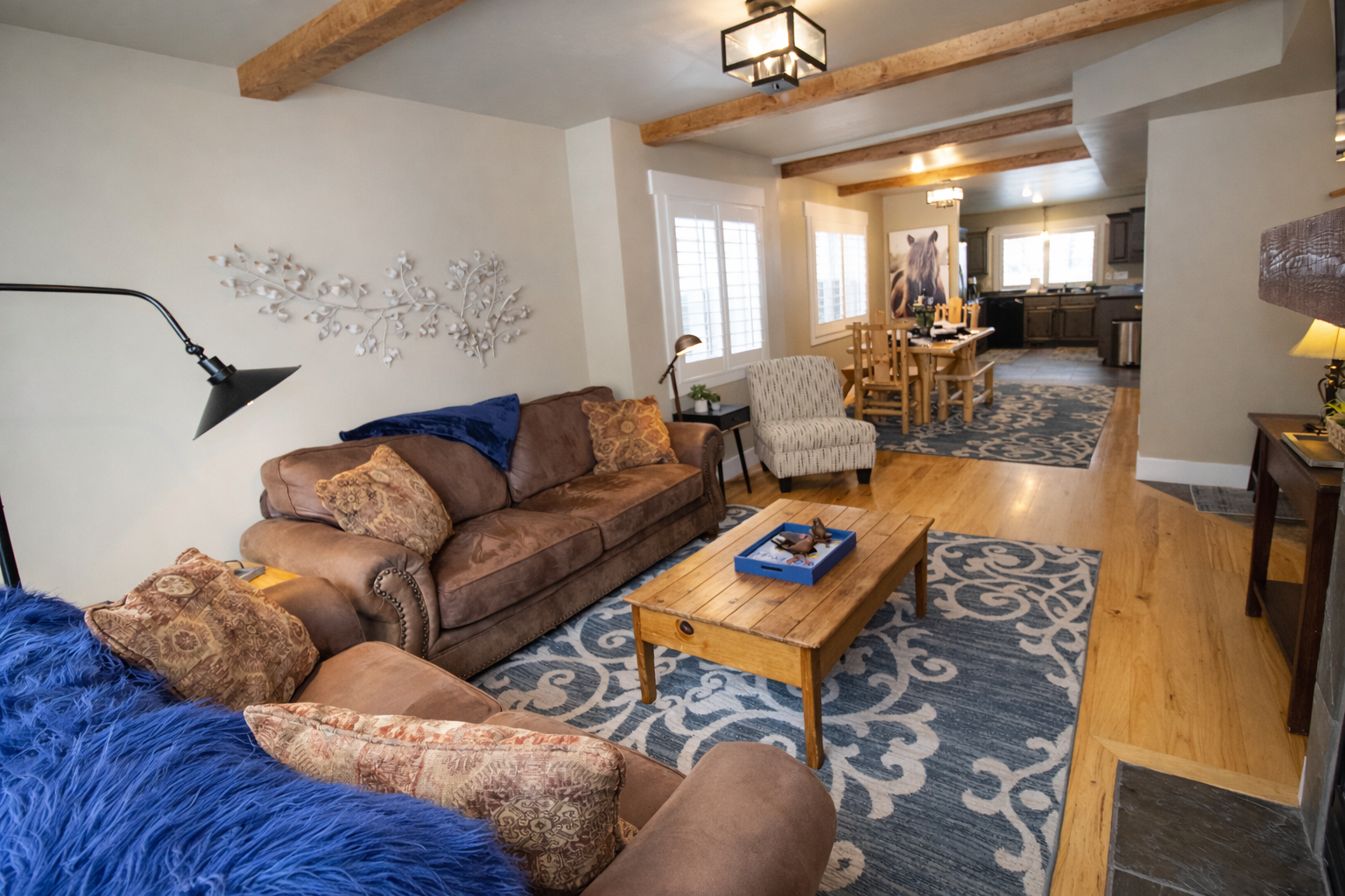 Unwind in your cozy living space featuring rustic beams, plush seating, and an open layout flowing into your fully equipped kitchen.