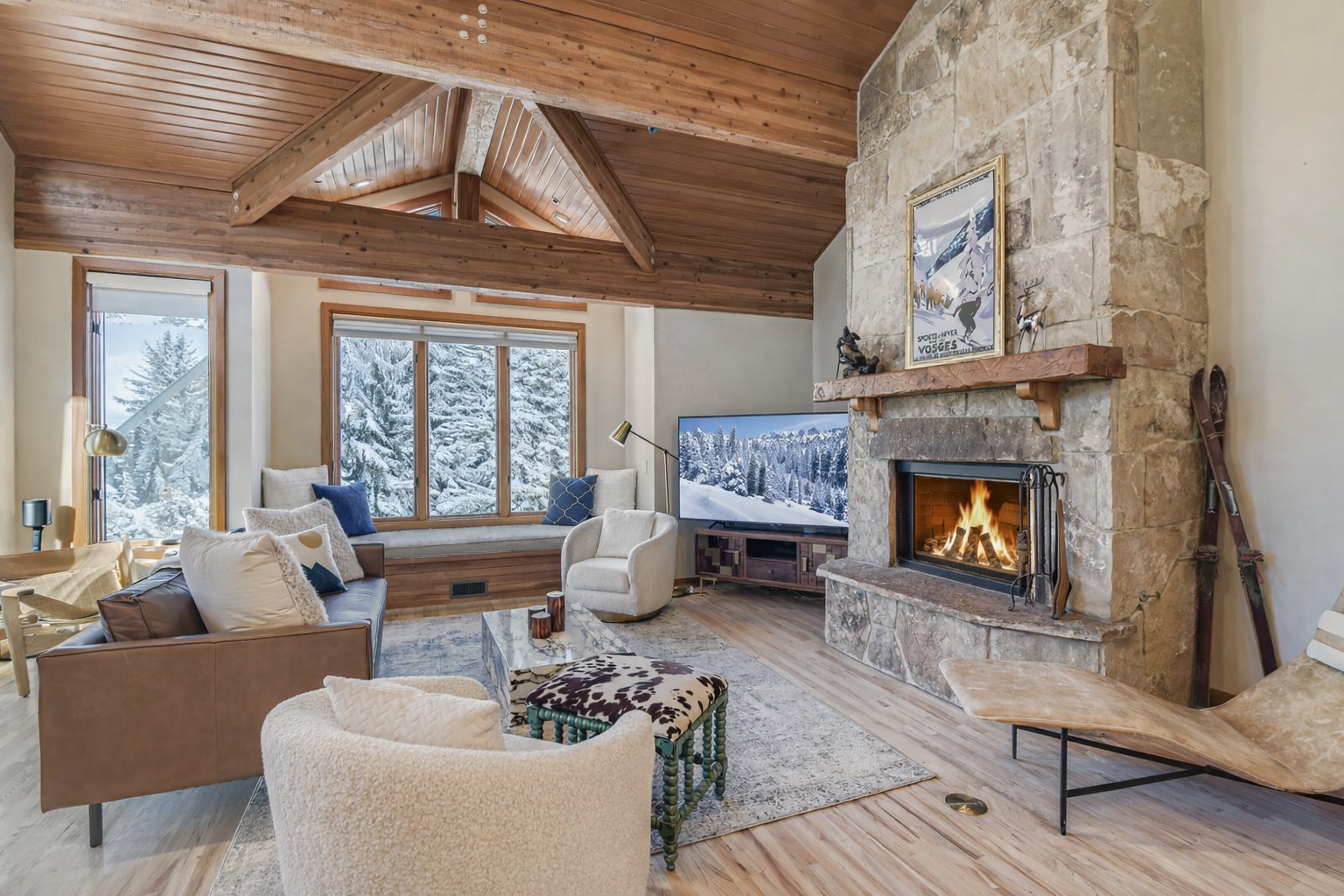 Escape to a cozy, rustic retreat! Enjoy this charming mountain living room featuring a stone fireplace, natural wood beams, and comfortable seating.