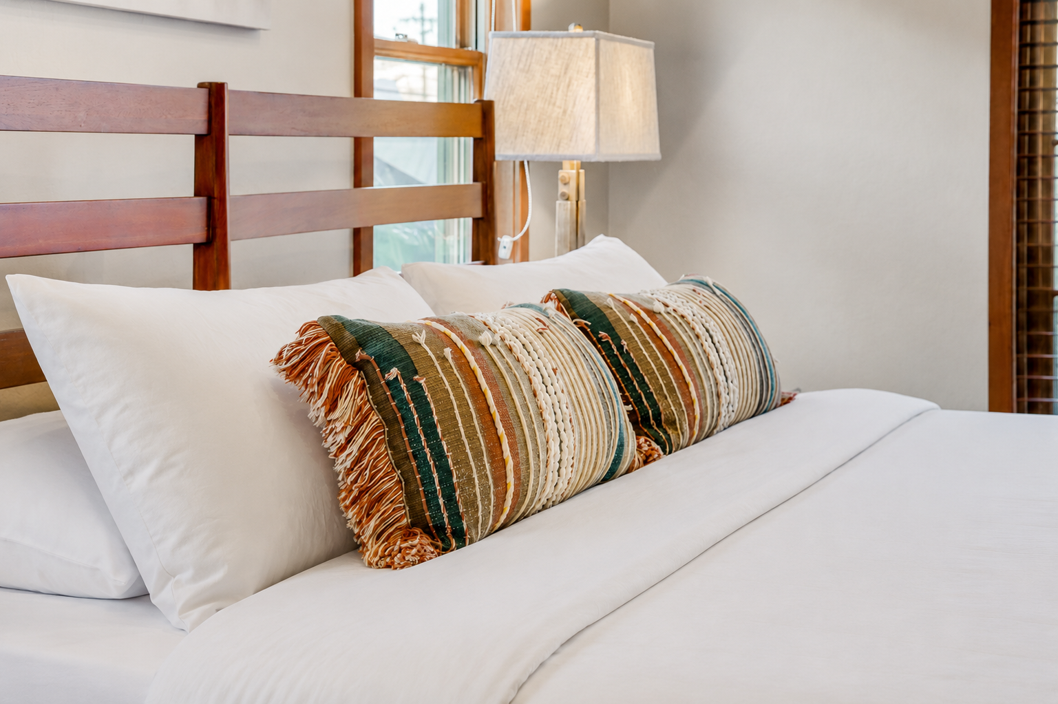 Sink into crisp white linens and plush pillows, with warm natural light framing your restful retreat.