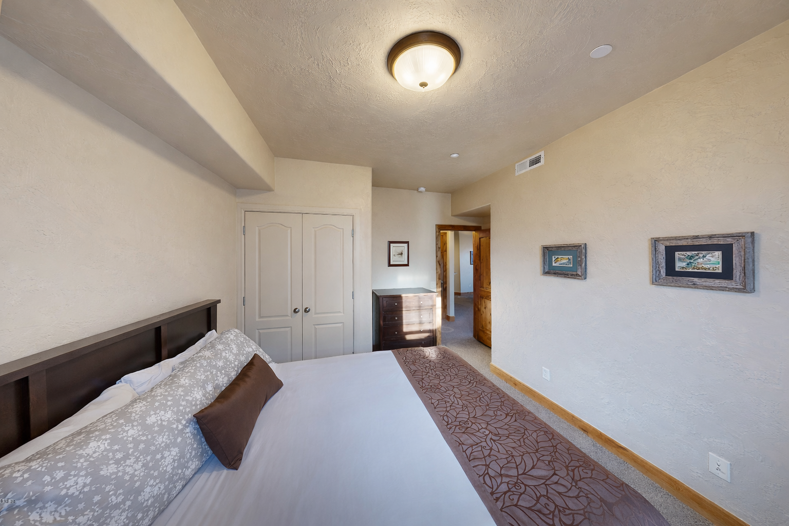 Relax in this cozy bedroom featuring a comfortable queen-size bed, nightstands with lamps, and ample closet/dresser storage space. A quiet retreat for rest and relaxation!