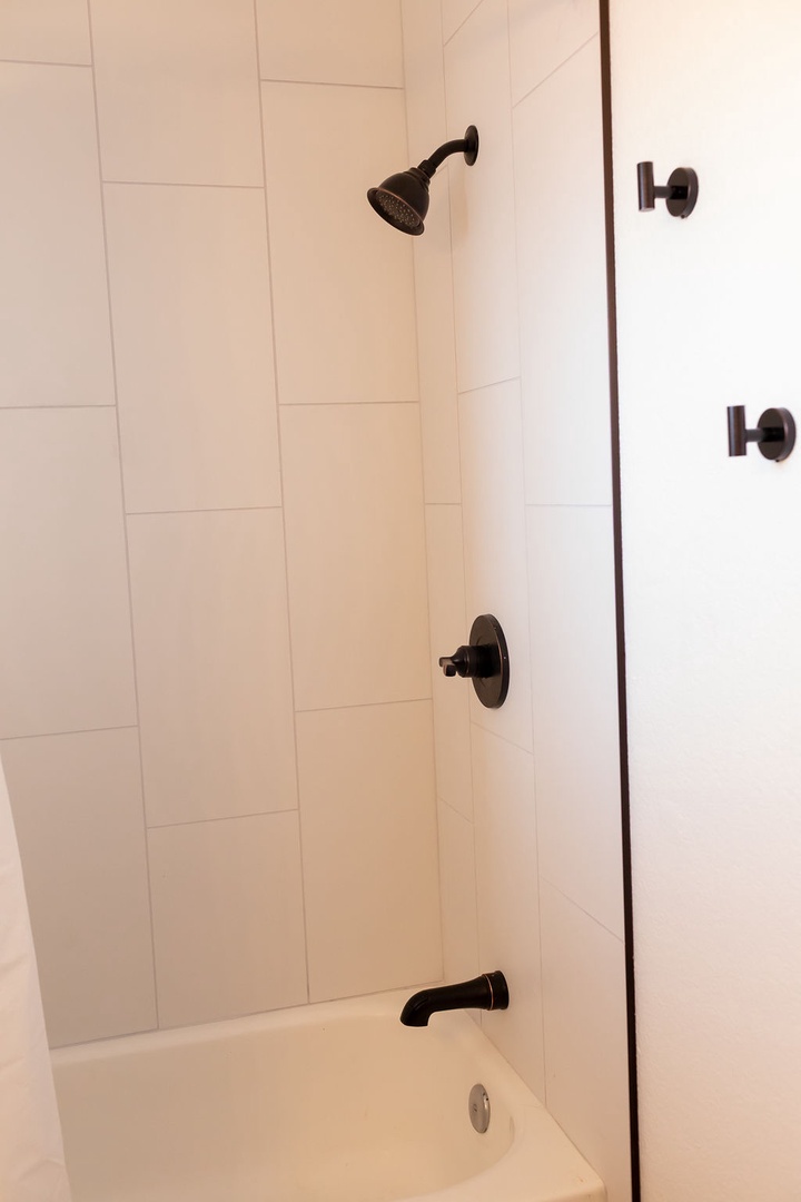 Step into your sleek bathroom featuring a spacious tub-shower combo with elegant subway tiles and stylish bronze fixtures for a refreshing retreat.