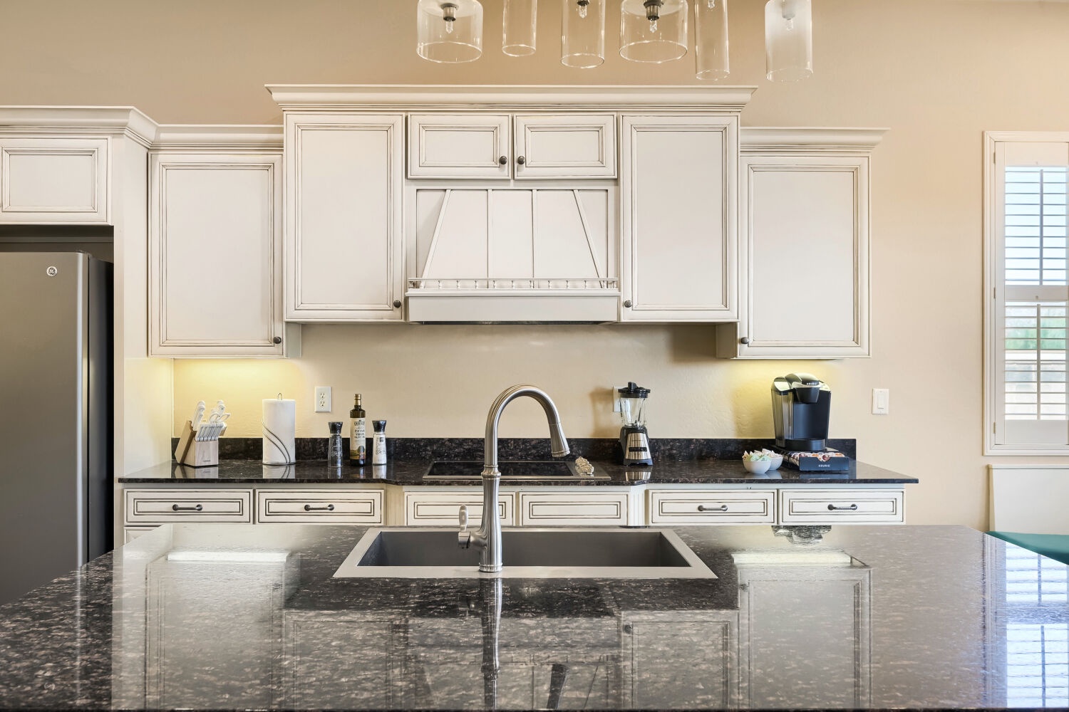 Your gourmet kitchen awaits with gleaming granite counters, a spacious island perfect for meal prep, and elegant white cabinetry that glows under soft accent lighting.
