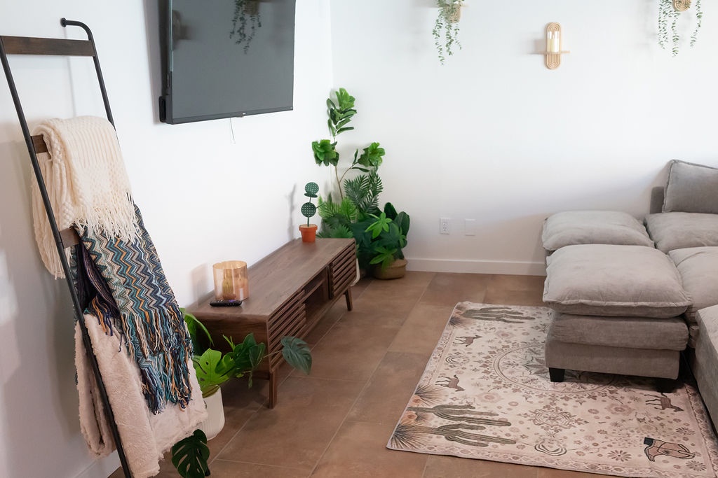 Sink into plush seating surrounded by lush greenery and natural light, where cozy throws invite relaxation.