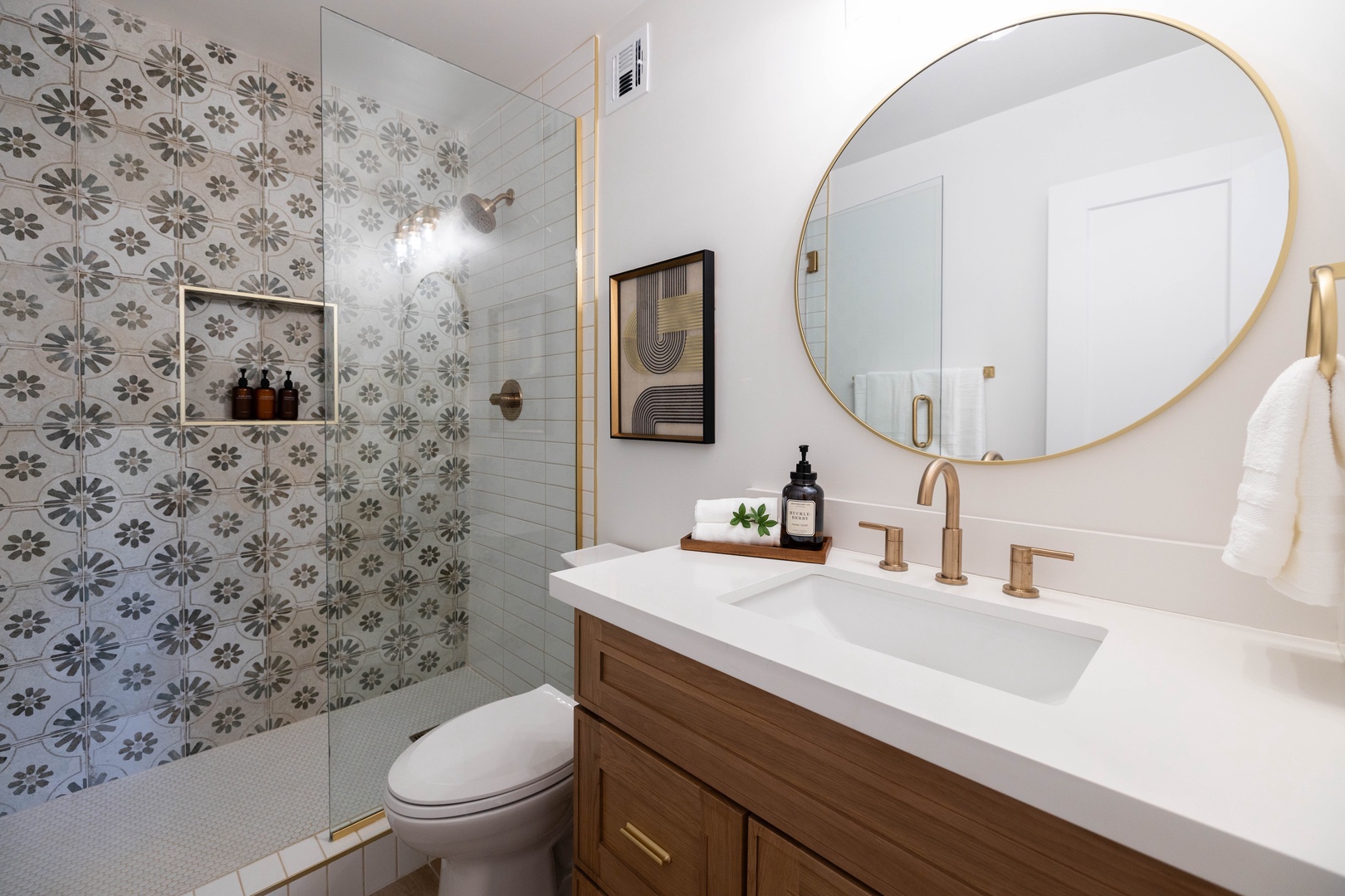 Step into this master en-suite bathroom where patterned tiles and warm brass fixtures elevate your morning routine.