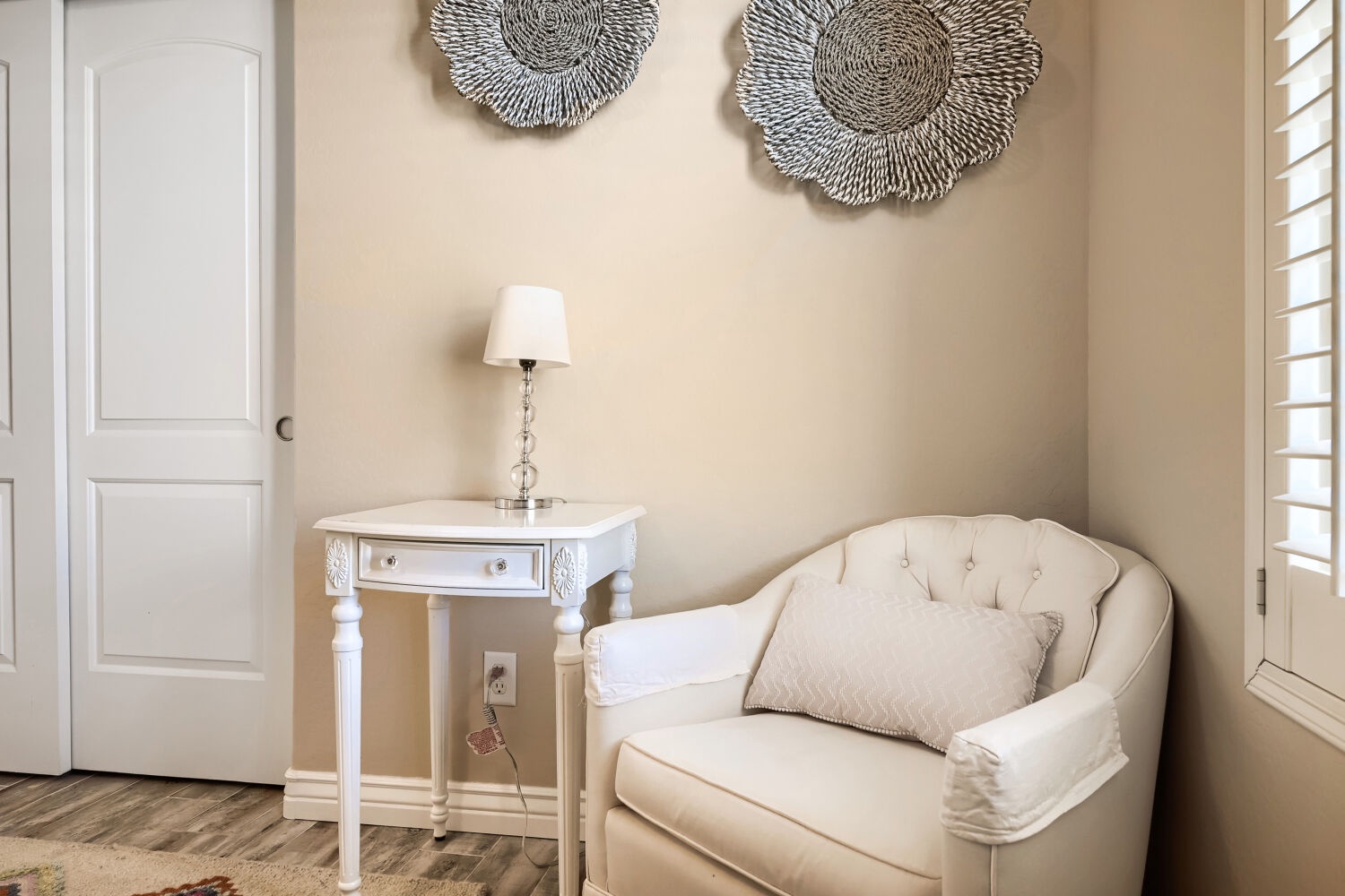 Sink into your private reading nook, where soft natural light filters through plantation shutters and elegant textures invite you to unwind with a good book.