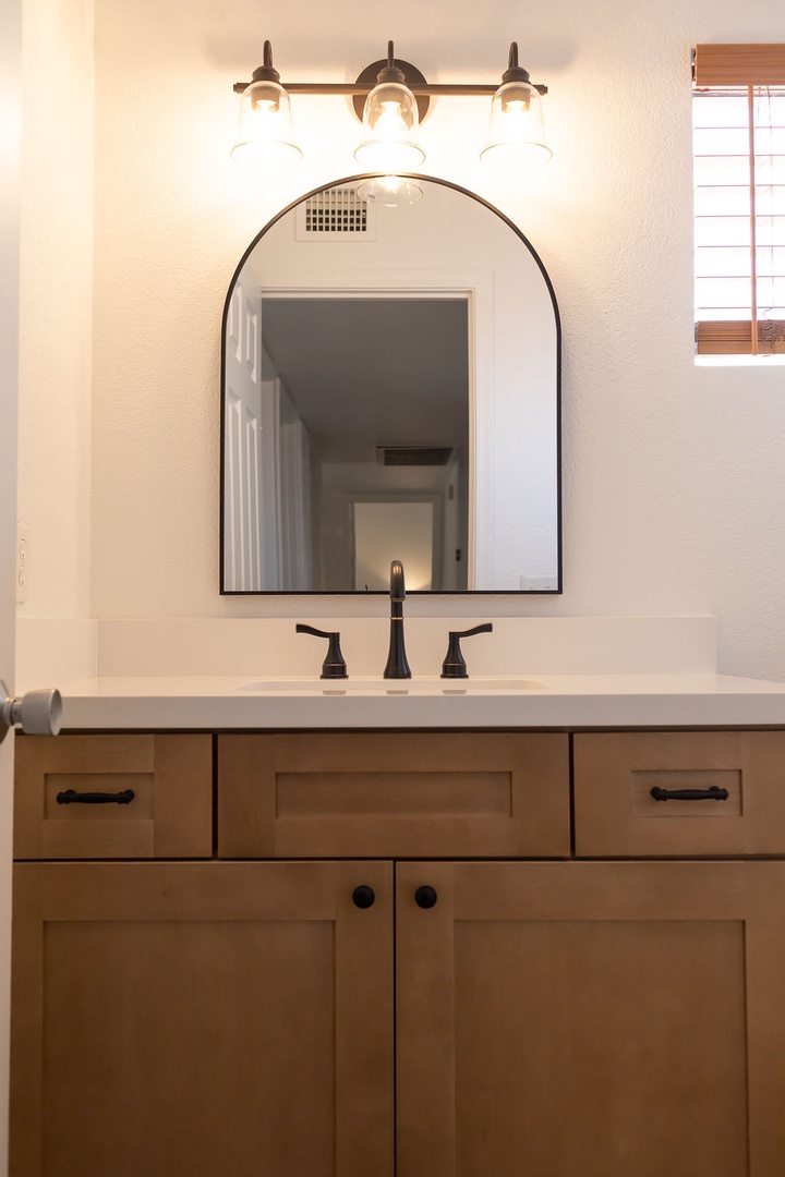 Start your mornings refreshed in this beautifully appointed bathroom, featuring warm wood vanity, elegant lighting, and thoughtful design details.