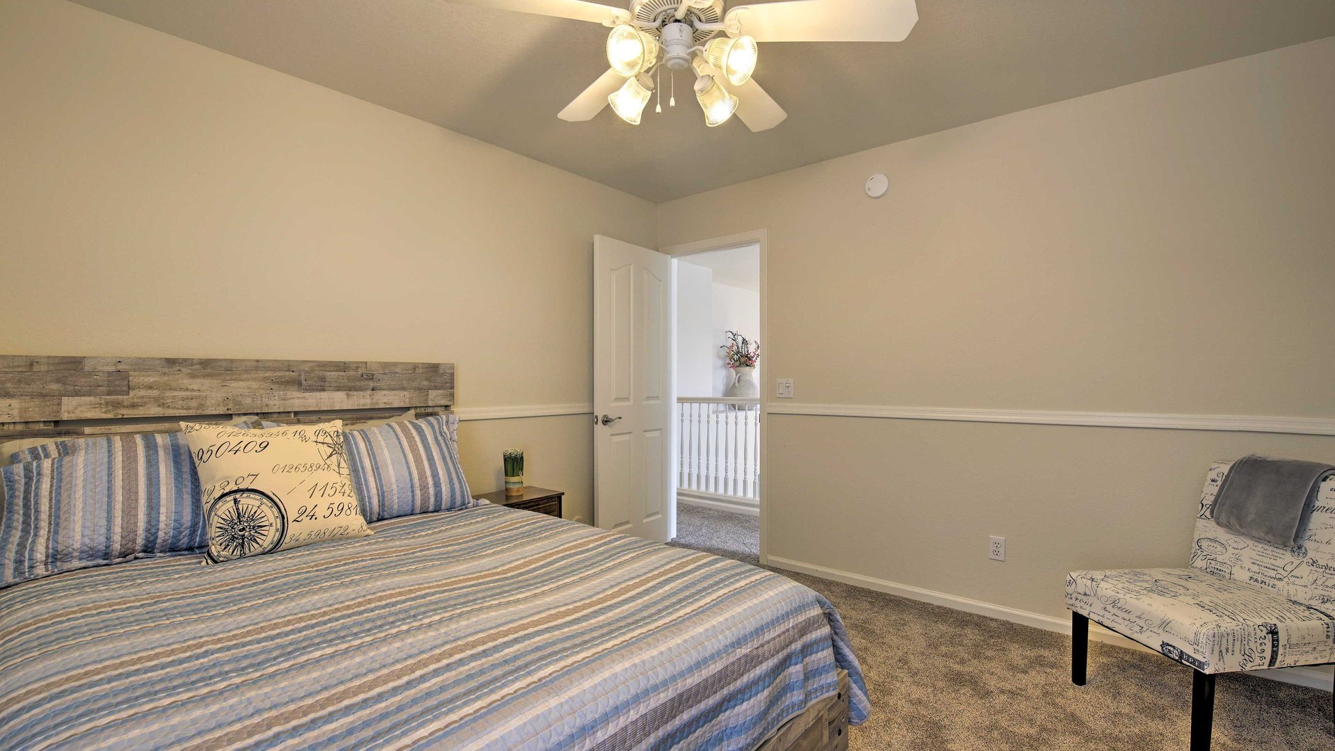 Relax in your peaceful 3rd queen bedroom featuring nautical accents, soft carpeting, and gentle ceiling fan breezes for perfect sleeping comfort.