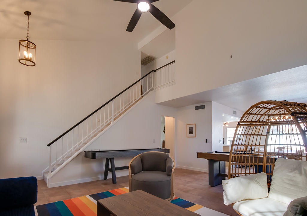 Unwind in your bright, airy living space with soaring ceilings, modern furnishings, and that stunning wicker hanging chair perfect for afternoon relaxation.