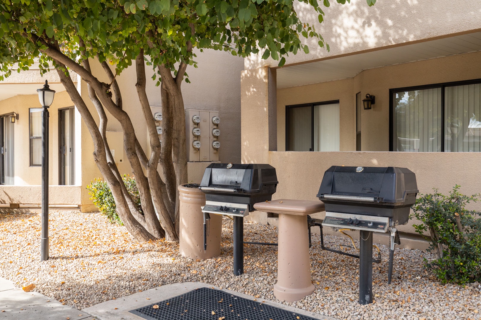 Fire up the grills for your perfect outdoor cookout under shaded trees in this inviting BBQ area.