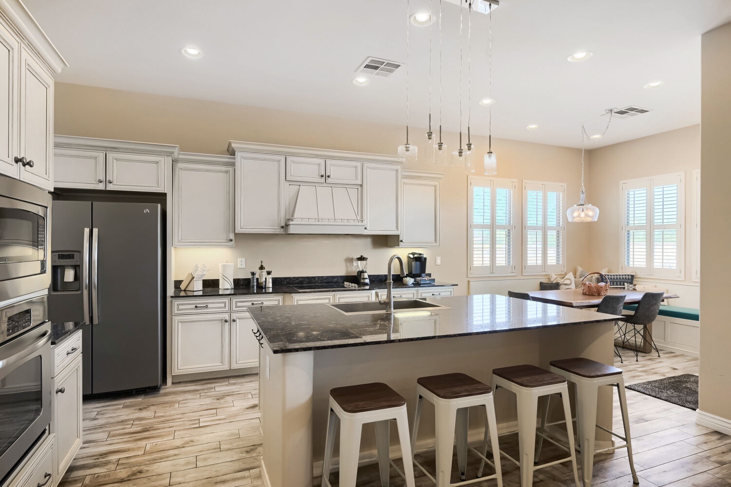 Your bright, modern kitchen awaits with sleek white cabinetry, dark granite counters, and a spacious island—perfect for gathering over morning coffee or preparing meals together.