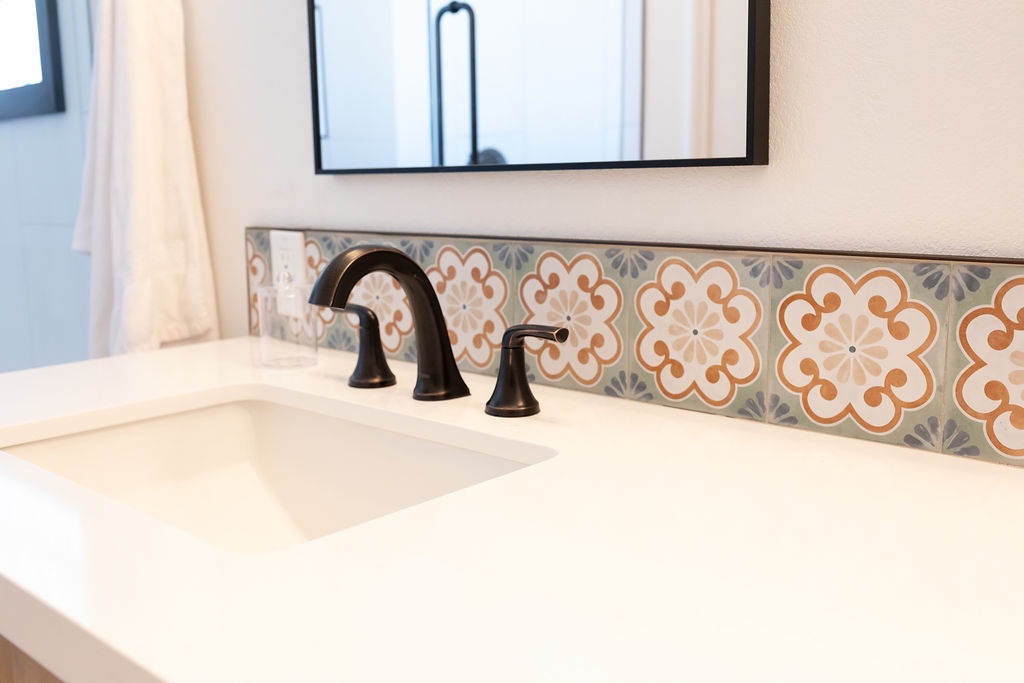 Freshen up at your stylish vanity with gorgeous Mediterranean-inspired tile backsplash and elegant bronze fixtures.