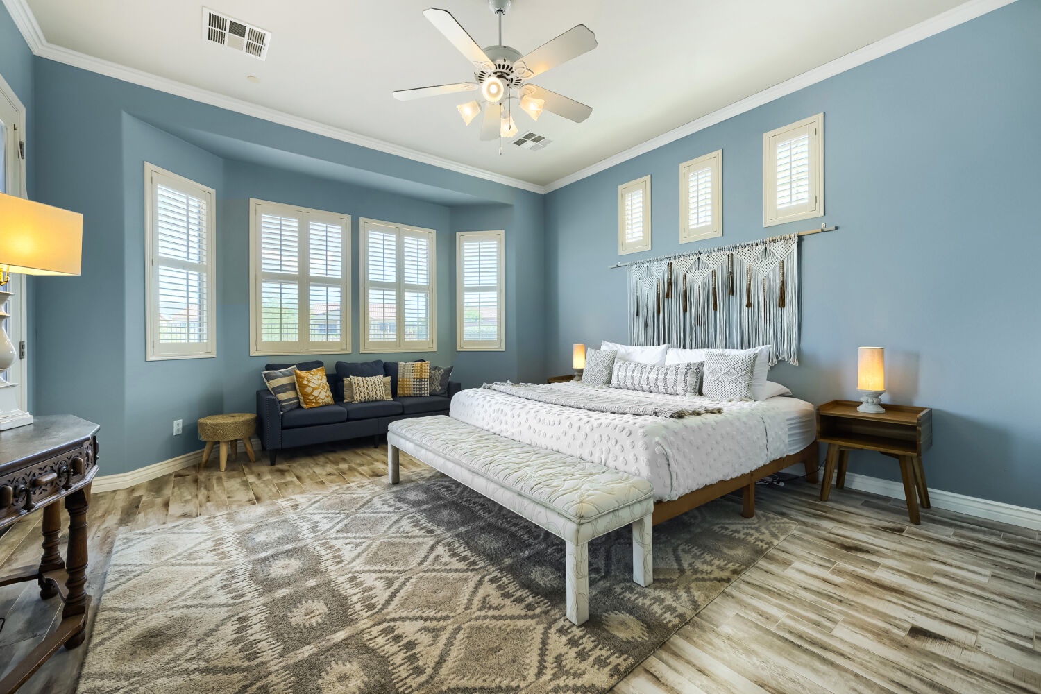Unwind in your serene bedroom retreat with calming blue walls, cozy seating by the windows, and ambient lighting that sets the perfect mood for rest.