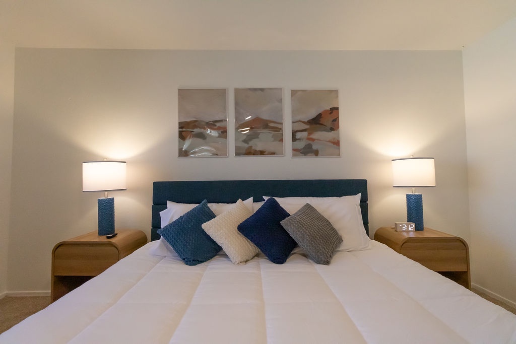 Sink into crisp white linens and plush pillows in your serene bedroom sanctuary, where warm bedside lighting creates the perfect atmosphere for relaxation.