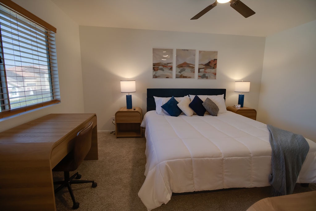 Sink into crisp white linens and plush pillows in your serene bedroom retreat, complete with work desk and peaceful ambiance.