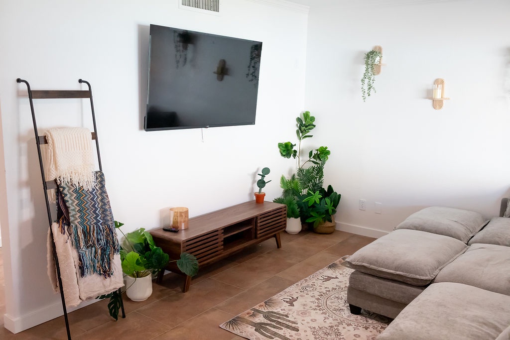 Sink into your spacious living room with plush seating, modern entertainment, and lush greenery creating the perfect atmosphere for relaxation.