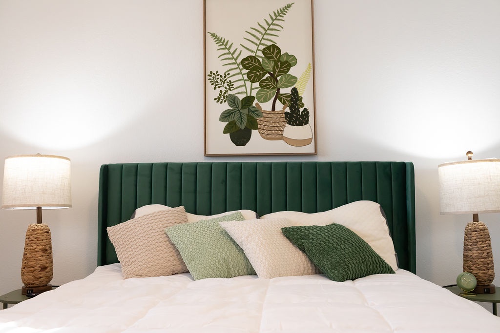 Sink into the plush white linens of your elegant bed, surrounded by warm botanical touches and soft lighting for the perfect restful retreat.