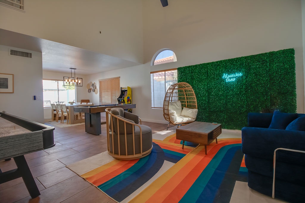 Relax in your vibrant living space with a unique hanging chair, colorful rainbow rug, and cozy seating areas perfect for unwinding after adventures.
