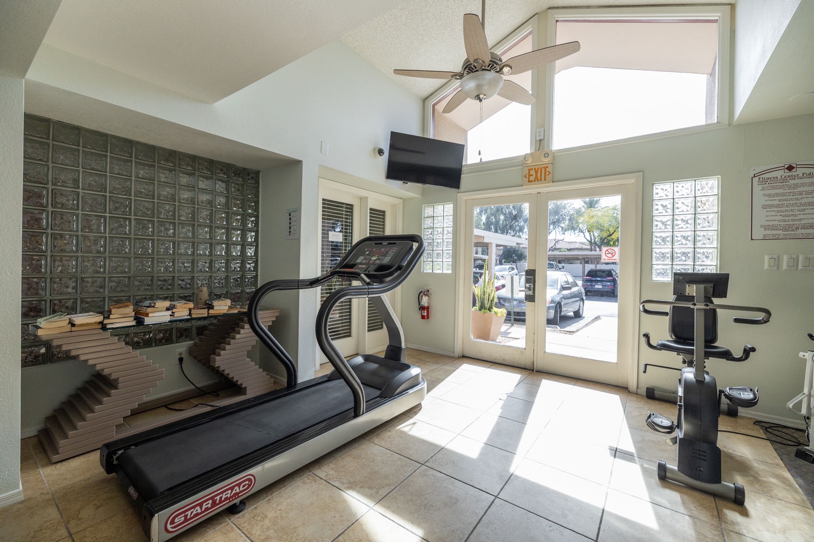 Stay active in your bright, modern fitness center featuring cardio equipment and strength training in a sunlit space.