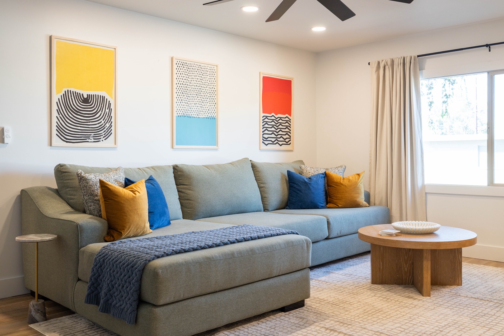 Unwind in your comfy living room with plush seating, vibrant artwork, and natural light.