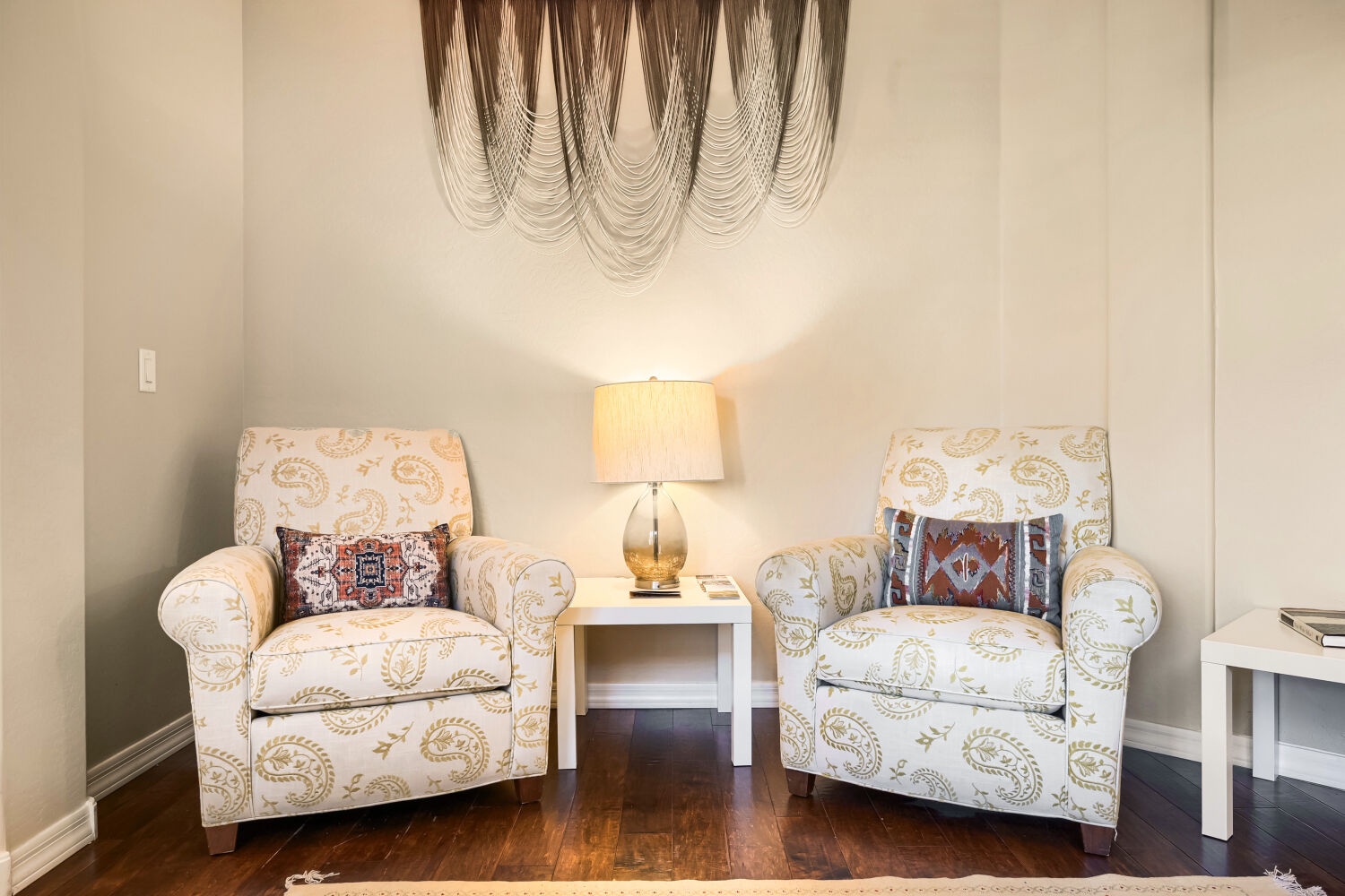 Step into a peaceful sitting area where twin upholstered chairs invite you to relax with morning coffee or a good book—soft lighting and warm textures make every moment feel like your own.