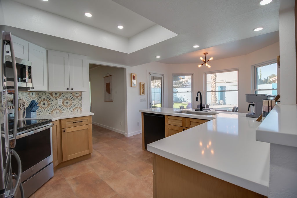 Your modern kitchen awaits with gleaming counters, stylish island seating, and beautiful tile backsplash - perfect for morning coffee or evening meals together.
