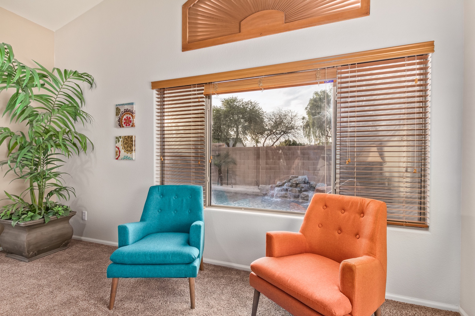 Unwind in your stylish seating nook with vibrant chairs and a stunning pool view through elegant blinds.