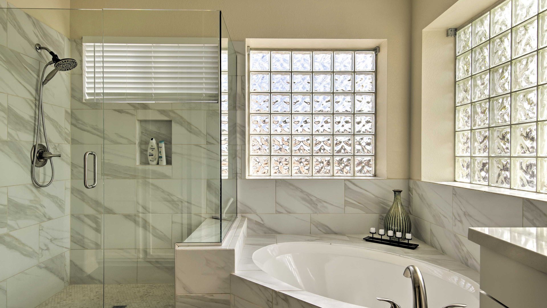 Unwind in your luxurious master bathroom featuring a marble-surround soaking tub and spacious glass shower