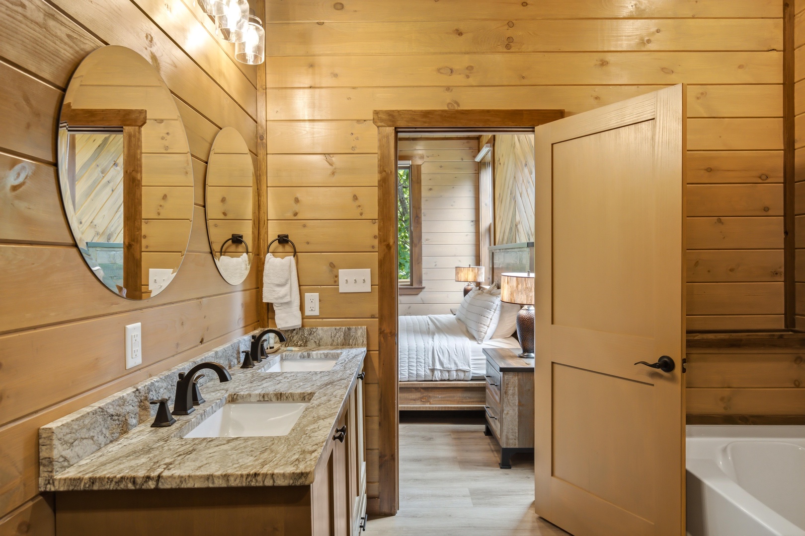 Your private bathroom features a granite dual vanity with warm wood accents, seamlessly connecting to a cozy bedroom space—perfect for unwinding after a day of adventure.