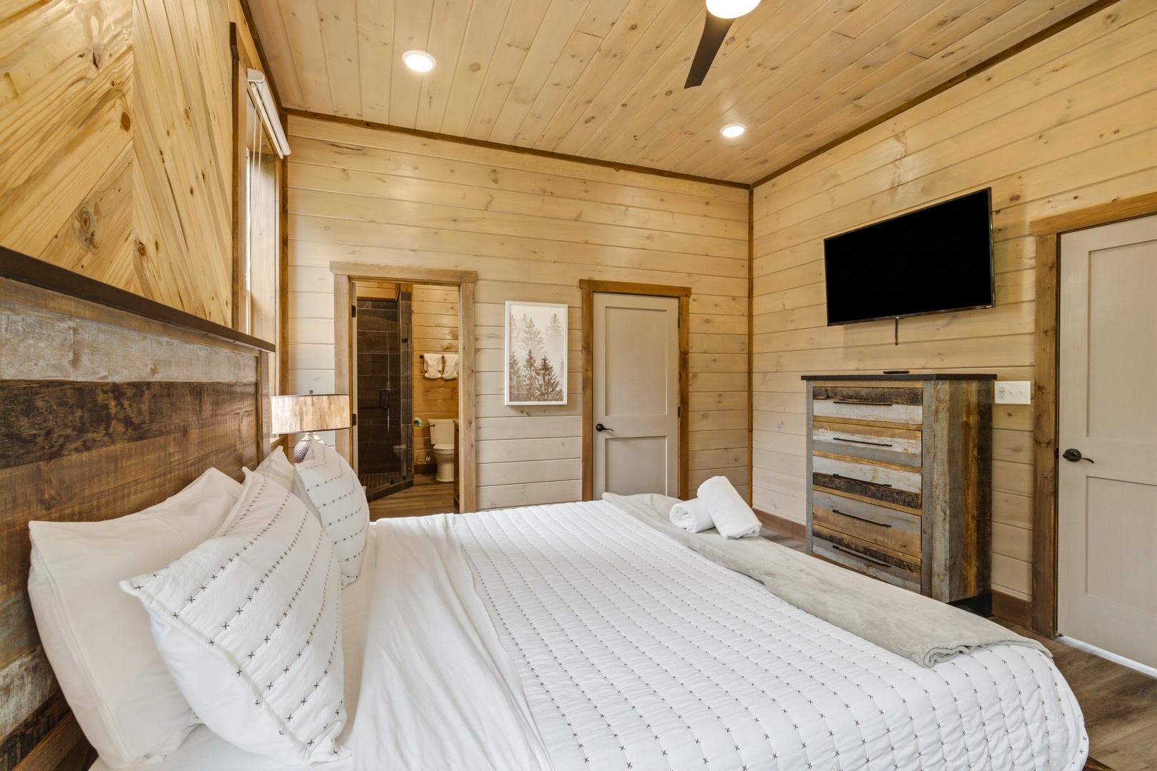 Unwind in your cozy retreat with warm wood tones and plush bedding. A private en-suite and flat-screen TV complete your comfortable escape.