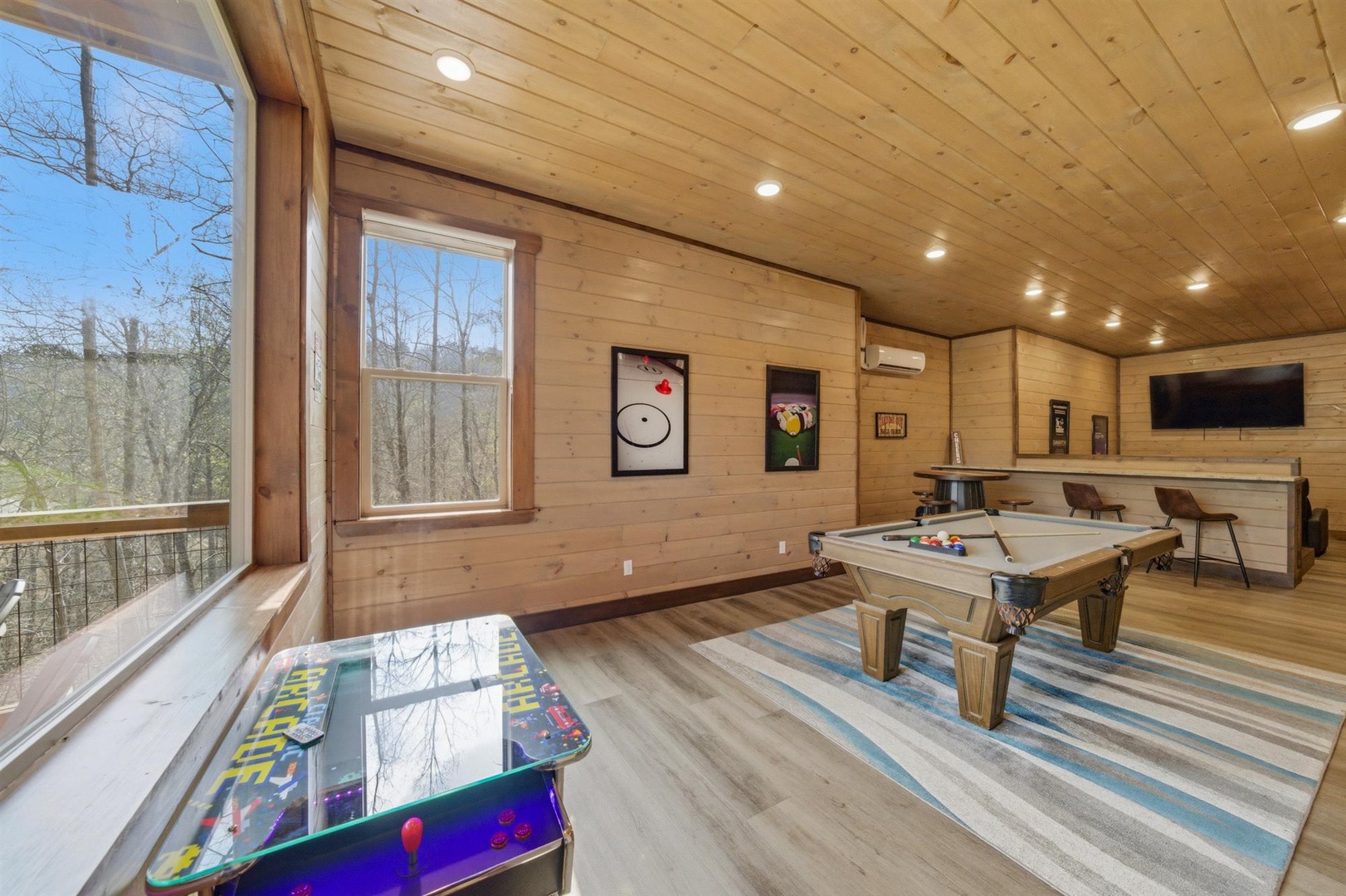 Your private game room awaits with pool table, arcade games, and mountain views through large windows—perfect for friendly competition and relaxation.