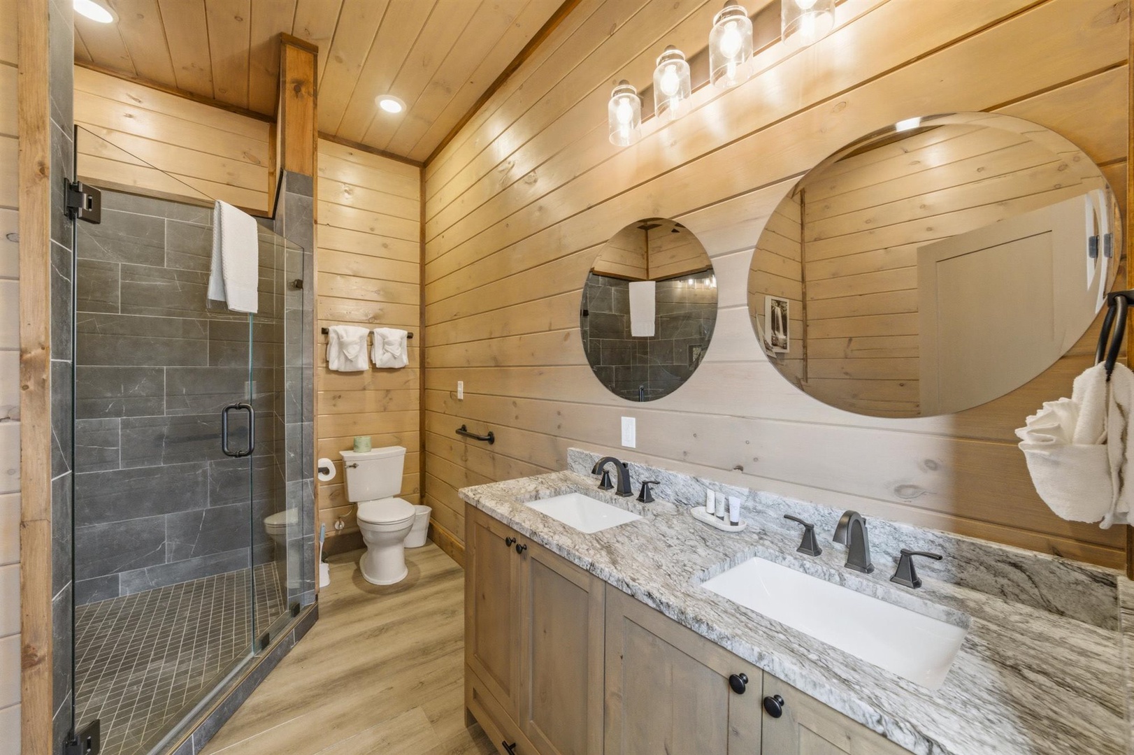 Unwind in your stunning rustic bathroom with dual vanities, rainfall shower, and warm wood accents creating the perfect mountain retreat atmosphere.