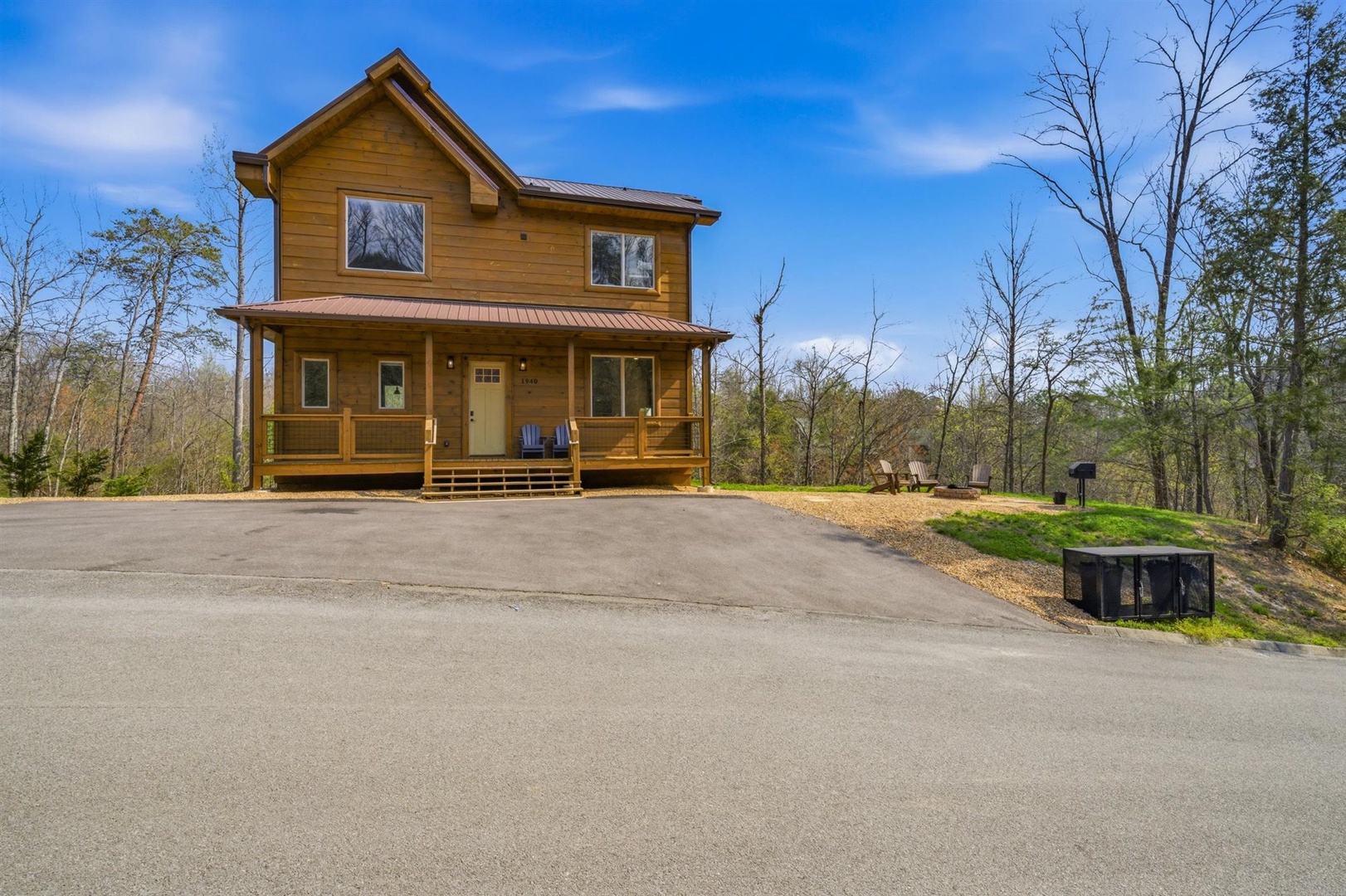 Charming two-story wooden cabin nestled among trees with convenient paved parking and peaceful wooded surroundings.