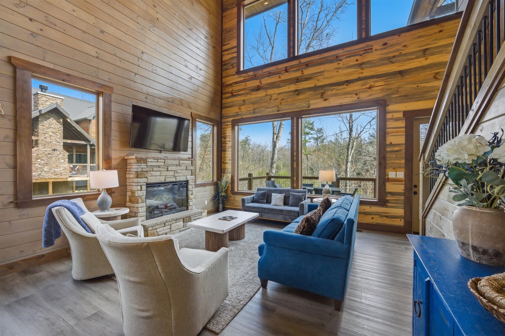 Unwind in your stunning great room, where soaring ceilings, warm wood walls, and floor-to-ceiling windows create the perfect mountain retreat atmosphere.
