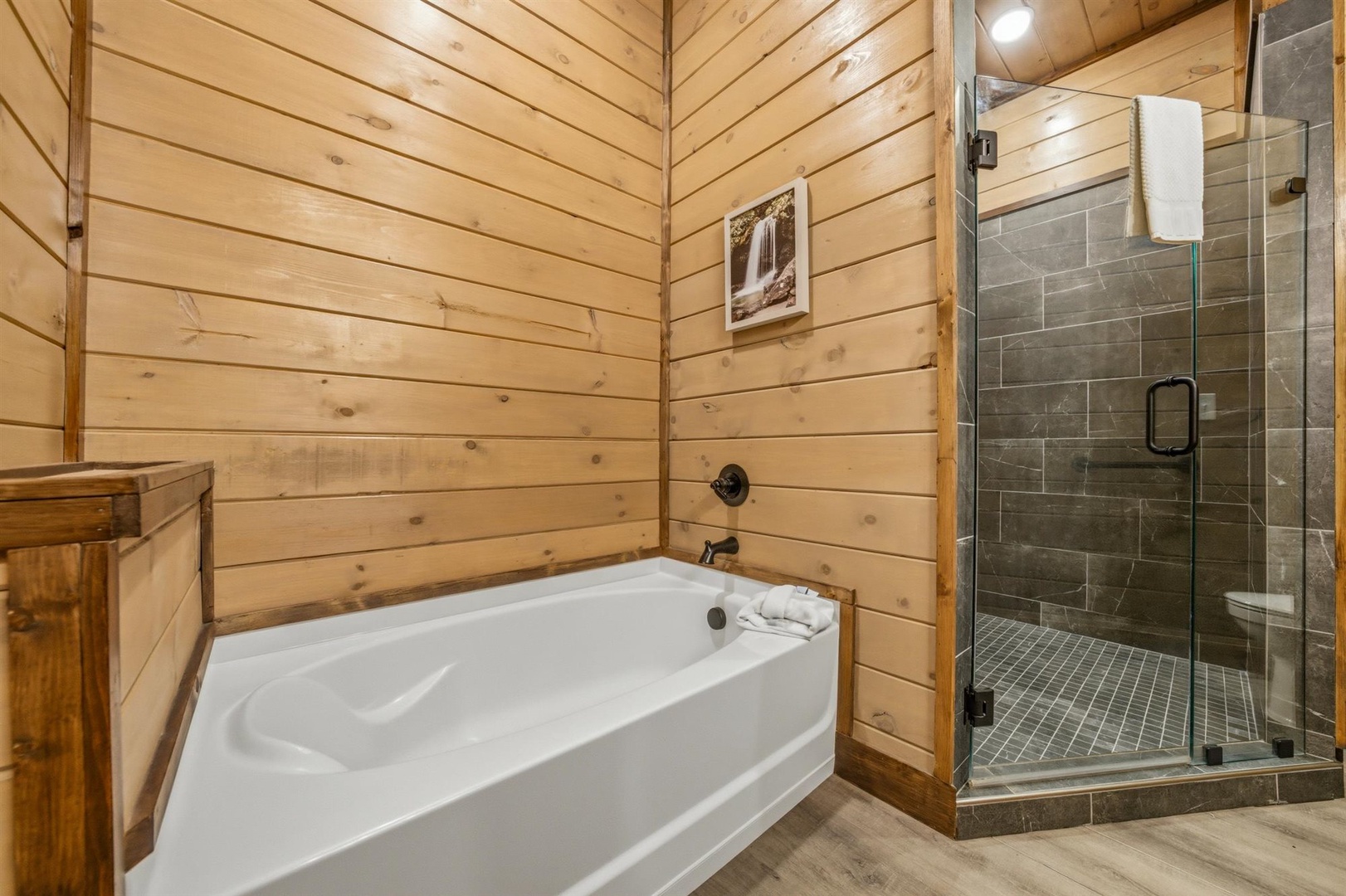 Unwind in your rustic spa-style bathroom featuring a deep soaking tub and walk-in shower with natural wood accents.