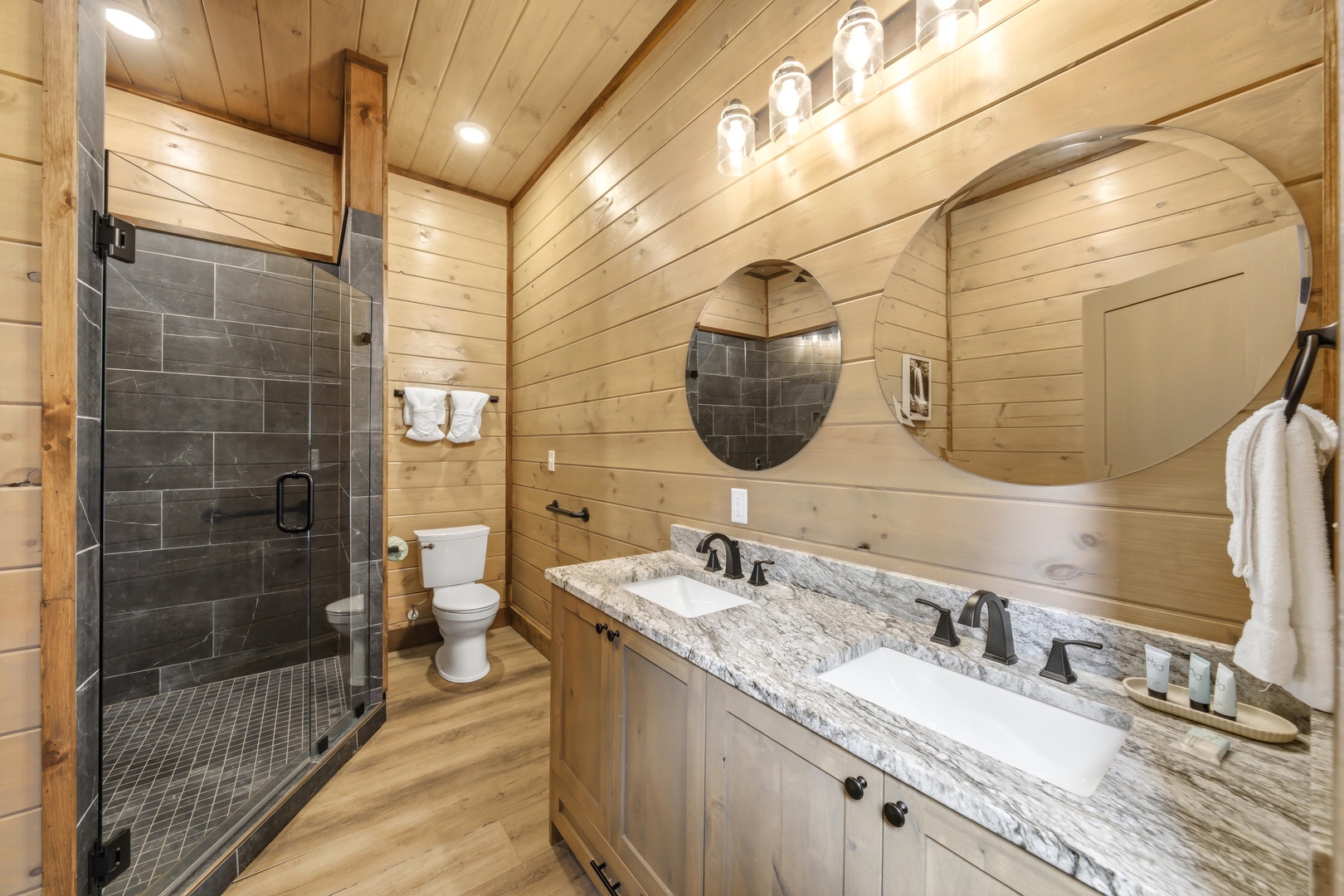 Your private spa-like bathroom features a spacious walk-in shower with elegant tile, double vanity, and warm wood-paneled walls that bring nature inside.